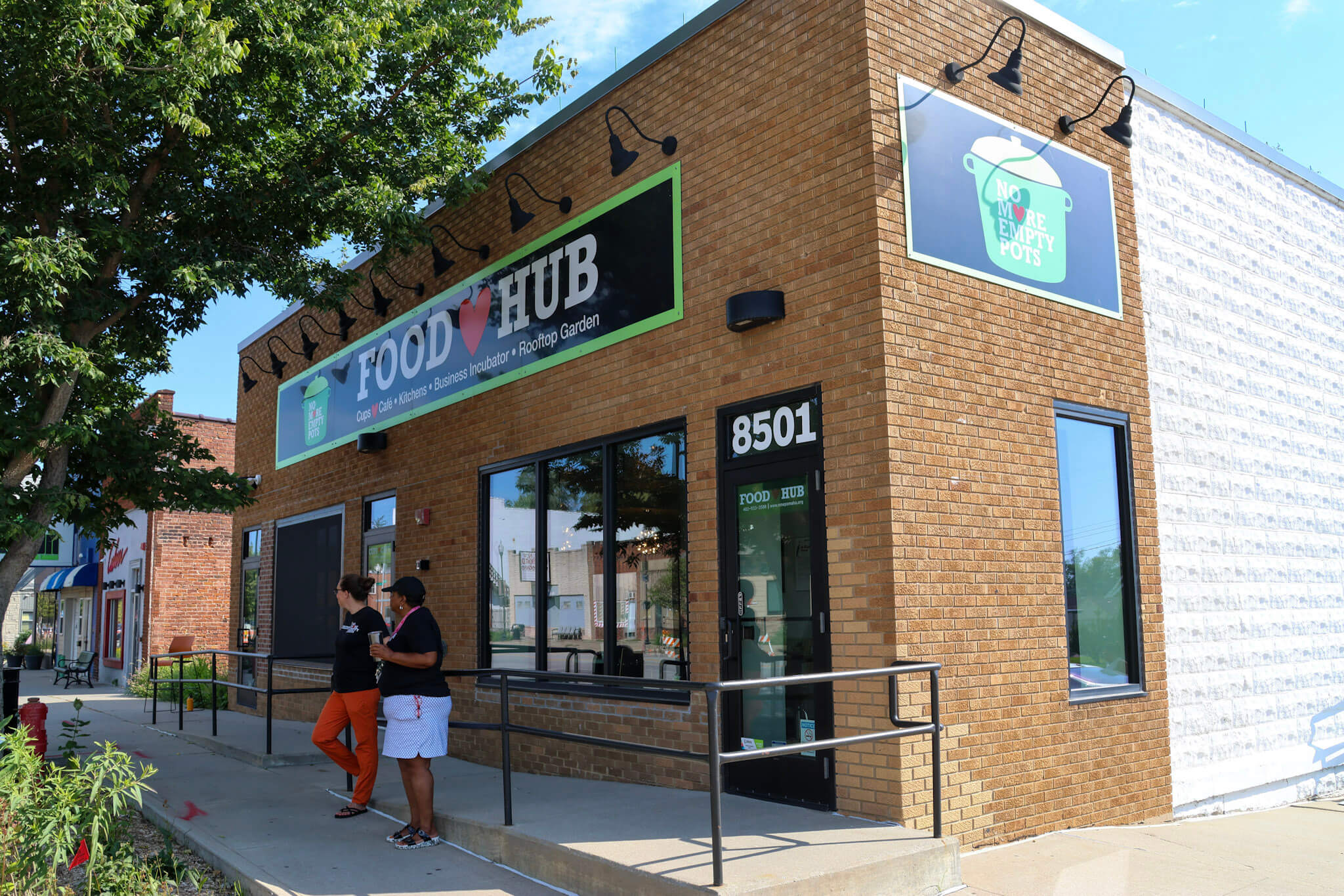 Two people standing outside of the No More Empty Pots building